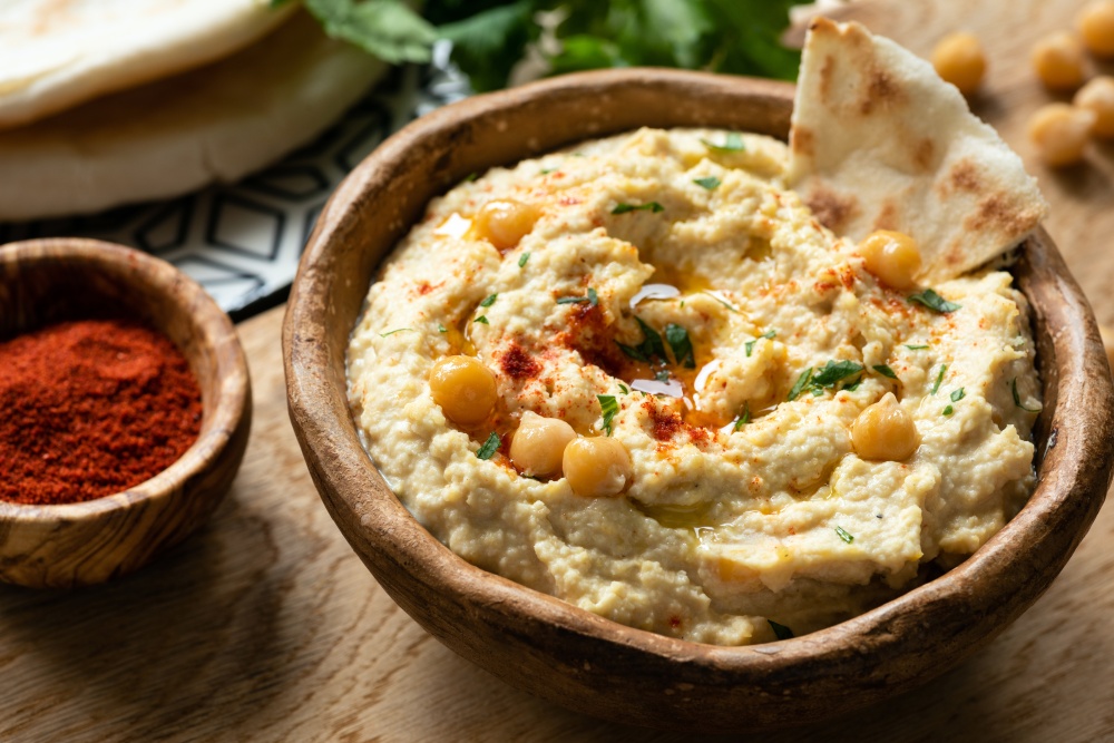 Homemade chickpea hummus in bowl served with pita bread and smoked paprika